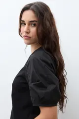 Remera negra de algodón con cuello redondo y mangas cortas abullonadas con detalle de frunces.