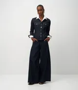 Campera de jean color azul oscuro, con diseño entallado, cuello camisero, mangas largas con puños abotonados y cierre frontal con botones metálicos. Presenta recortes estructurales que realzan la silueta.