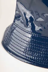 Gorro tipo bucket impermeable de acabado brillante, color negro, con costuras horizontales en el ala.