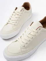 Championes urbanos de diseño minimalista en color beige, con suela de goma blanca y detalles en color marrón en el interior y borde del cuello.
