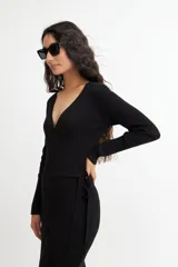 Vestido midi color crema, tejido en punto acanalado, con escote cruzado en V, mangas largas y lazo ajustable en la cintura.