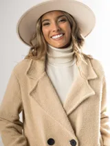 Tapado clásico color beige, con solapas de muesca, doble botonadura y bolsillos laterales.