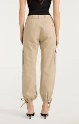 Pantalón cargo color beige de tiro alto, con bolsillos laterales con solapa y ajuste con lazos en los tobillos.