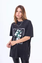 Remera de algodón con efecto acid wash en color negro, de corte oversize y manga corta. Presenta un estampado frontal enmarcado que ilustra un jarrón con flores blancas.