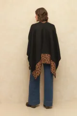 Poncho negro con estampado animal print en el borde inferior y cierre con alamar dorado.