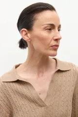 Sweater azul marino de tejido de punto con cuello polo y escote en V. Presenta un diseño de trenzas verticales en toda la prenda y mangas largas.