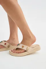 Ojotas de dedo negras con suela plana y gruesa, decoradas con apliques metálicos de piedras de colores en la tira.