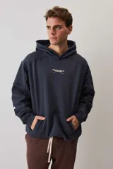 Hoodie canguro de friza en color azul marino, con capucha ajustable, bolsillo frontal tipo parche y estampa tipográfica pequeña en el pecho.