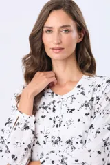 Blusa blanca de manga larga con estampado floral en negro, cuello redondo y botones frontales personalizados.