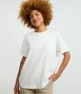 Remera de corte boxy con cuello redondo y mangas cortas. Confeccionada en algodón, presenta un diseño minimalista sin estampas con sisa caída.