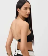 Top de bikini bandeau de microfibra con diseño color block en color negro y blanco, fruncido central y detalle metálico.