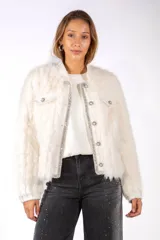 Chaqueta de piel sintética color blanco, con diseño de corte recto y cuello redondo. Presenta detalles de bordes con pedrería brillante y botones decorativos con perlas en el cierre frontal y bolsillos superiores.