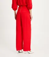 Pantalón recto de crepé rojo, con tiro medio, superposición decorativa en la cintura con botones forrados y cierre trasero.