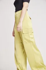 Pantalón de vestir color verde oliva, de corte ancho y tiro alto, con bolsillos laterales tipo cargo y detalle de pinzas en la cintura.