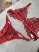 Conjunto de lencería de encaje rojo, compuesto por un bralette de diseño geométrico con tiras elásticas y una tanga con detalles de aberturas laterales.