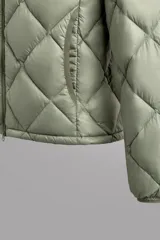 Campera puffer verde oliva acolchada con diseño de rombos, capucha y cierre frontal con cremallera. Incluye bolsillos laterales con cierre. Relleno de plumón y plumas.