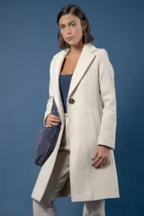 Tapado de corte sastre en color crudo, con solapas clásicas, cierre frontal de un botón y bolsillos laterales. Presenta una silueta estructurada y elegante.