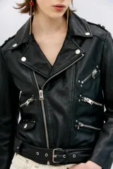 Campera estilo biker confeccionada en cuero ovino, con solapas amplias, charreteras en los hombros y cinturón ajustable en la cintura. Presenta cierres metálicos en el frente y bolsillos laterales, con forro interior de poliéster.