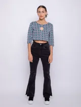 Top corto negro con estampado de líneas onduladas blancas, mangas 3/4 y abertura circular en el pecho.