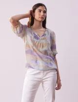 Blusa de gasa estampada con cuello a la base, escote en V plisado y lazo de ajuste. Delantera con detalles en puntilla y manga corta con puño fruncido.