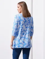 Blusa amarilla estampada con motivos florales en blanco, escote en V y mangas tres cuartos.