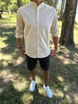 Camisa de manga larga color beige con cuello mao y cierre frontal de botones.