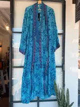 Kimono largo de tela estampada con motivos abstractos en tonos azules, verdes y beige. Diseño de manga ancha y corte recto, sin cierres.