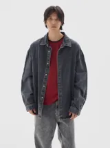 Camisa de denim de manga larga con cuello clásico, cierre frontal de botones y diseño oversize con lavado tipo washed.