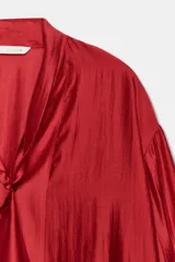 Camisa de ZARA Woman Collection confeccionada en hilatura con mezcla de lyocell, de color blanco marfil. Presenta cuello redondo, escote en V con lazadas en el mismo tejido, manga larga con puño y bajo recto.