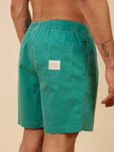 Short de baño tipo volley color amarillo claro, con cintura elástica y cordón ajustable. Presenta un diseño liso con un pequeño logo bordado en la parte inferior de la pierna izquierda.