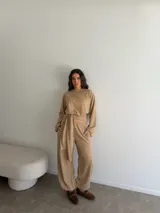 Conjunto de dos piezas compuesto por una remera de manga larga con diseño cruzado y lazo ajustable en la cintura, y un pantalón largo de corte holgado con bolsillos laterales y cintura elástica.