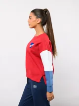 Buzo de cuello redondo con diseño de bloques de color en rojo, blanco y azul. Presenta el logo de Umbro y el escudo del Club Nacional de Football bordados en el pecho.