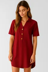 Túnica de lino color bordó, con cuello camisero, cierre frontal parcial con botones y mangas cortas. Presenta un corte holgado con ruedo redondeado.