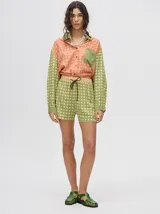 Short de corte boxy con estampado geométrico de círculos en tonos verde y beige. Presenta una pretina elástica con cordón de ajuste en color marrón oscuro.