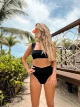 Conjunto de bikini negro de hilo, con corpiño bandeau y bombacha vedetina de tiro alto.