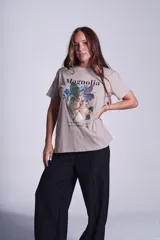 Remera blanca de algodón con estampado de flores de magnolia y texto en negro.