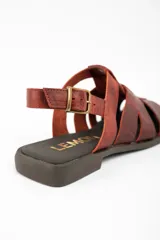 Sandalia tipo cangrejera de cuero lavado color marrón rojizo, con diseño de tiras entrelazadas, puntera cerrada y ajuste mediante correa con hebilla metálica en el tobillo.
