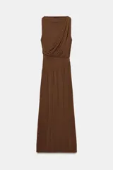 Vestido largo sin mangas de cuello redondo, confeccionado en tejido drapeado con detalle de cintura tipo fajín en el mismo material.