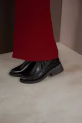 Bota corta de cuero marrón con panel trasero de gamuza en tono más oscuro, suela de goma negra y taco cuadrado bajo.