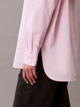 Camisa de corte relaxed confeccionada en popelina de algodón con elastano. Presenta cuello de punta clásico, cierre frontal con botones, mangas largas y un bolsillo en el pecho con el monograma CK bordado en relieve.