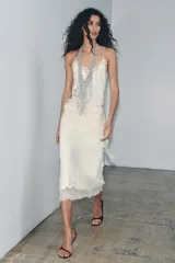 Falda midi de punto liso color crema, con cintura elástica y bajo acampanado. El ruedo está decorado con bordados, abalorios y encaje a tono.