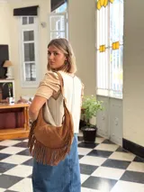 Cartera bandolera de cuero color camel con flecos largos en la parte inferior.