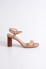 Sandalia de cuero color peltre, con tira ancha sobre los dedos y tira fina con hebilla al tobillo. El taco es cilíndrico de madera clara.