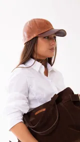 Gorra de estilo baseball confeccionada en cuero, con diseño combinado en tonos camel y visera en marrón chocolate.