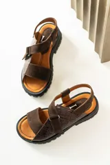 Sandalias de cuero con diseño combinado en gamuza marrón y cuero con textura de reptil. Presentan tiras ajustables con velcro, plantilla acolchada color suela y suela de goma tipo track con relieve.