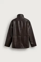 Cazadora de corte relaxed fit confeccionada en tejido efecto piel de color marrón. Cuenta con cuello subido forrado en su interior con tejido de cuadros, manga larga, bolsillos de vivo en la cadera y un bolsillo interior. El cierre frontal es con cremallera oculta por una solapa con botones a presión.