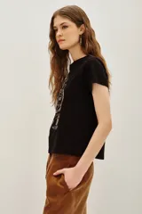 Remera negra de algodón con estampa frontal de un tigre realizada con aplicaciones de cuentas y bordados. Presenta mangas cortas con dobladillo y corte holgado.