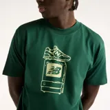 Remera New Balance de hombre, color verde oscuro, de manga corta y corte amplio. Presenta un estampado frontal de estilo pixel art inspirado en el efecto 2000 que representa un televisor retro y un champión.