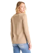 Buzo de tejido fino con acabado brillante de lurex, color beige, con escote en V, mangas largas con puños acanalados y ruedo con detalle de tejido acanalado más ancho.