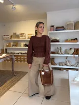 Blusa color chocolate con diseño de frunces elásticos en el frente y la espalda, mangas largas abullonadas con puños elásticos y corte peplum.